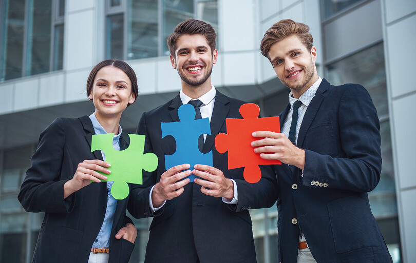 Equipo de profesionales sosteniendo piezas de rompecabezas como símbolo de trabajo conjunto